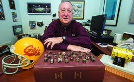 Dave Guffey has accrued quite the collection of Griz memorabilia during his career, including twenty-six championship rings perched here atop The Red Book. The two he wears are from national championships. (Photo by Todd Goodrich)